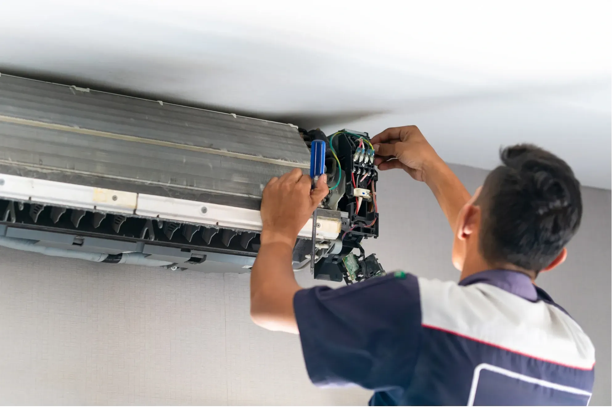 Teknisi memasang ulang papan sirkuit unit AC indoor